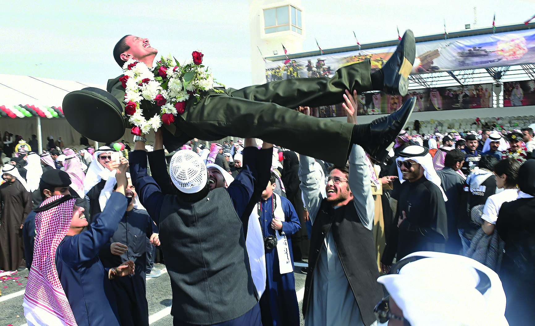 ذوو خريج يرفعونه في الهواء فرحاً بتخرجه