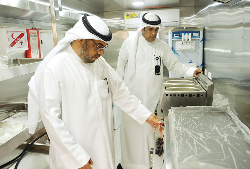 مفتشان من إدارة غذاء الفروانية يتفحصان تجهيزات سيارة من الداخل