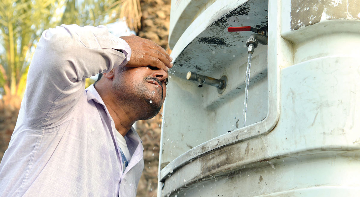 عامل يخفف عن نفسه حرارة الشمس بمياه أحد البرادات 	(تصوير نايف العقلة)
