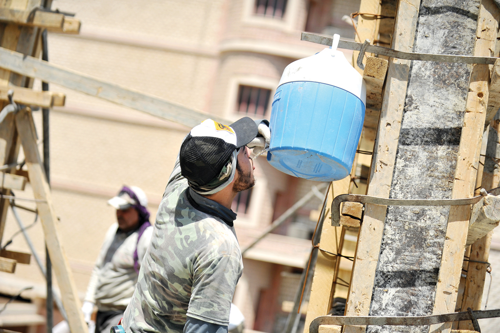 عامل يشرب ماء في ظل أشعة الشمس الحارقة 	