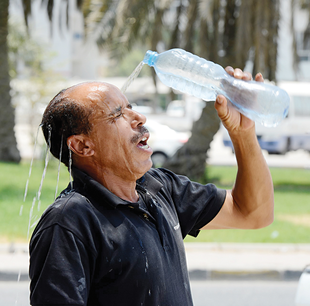 عامل يصب الماء على رأسه لتخفيف حدة الحر