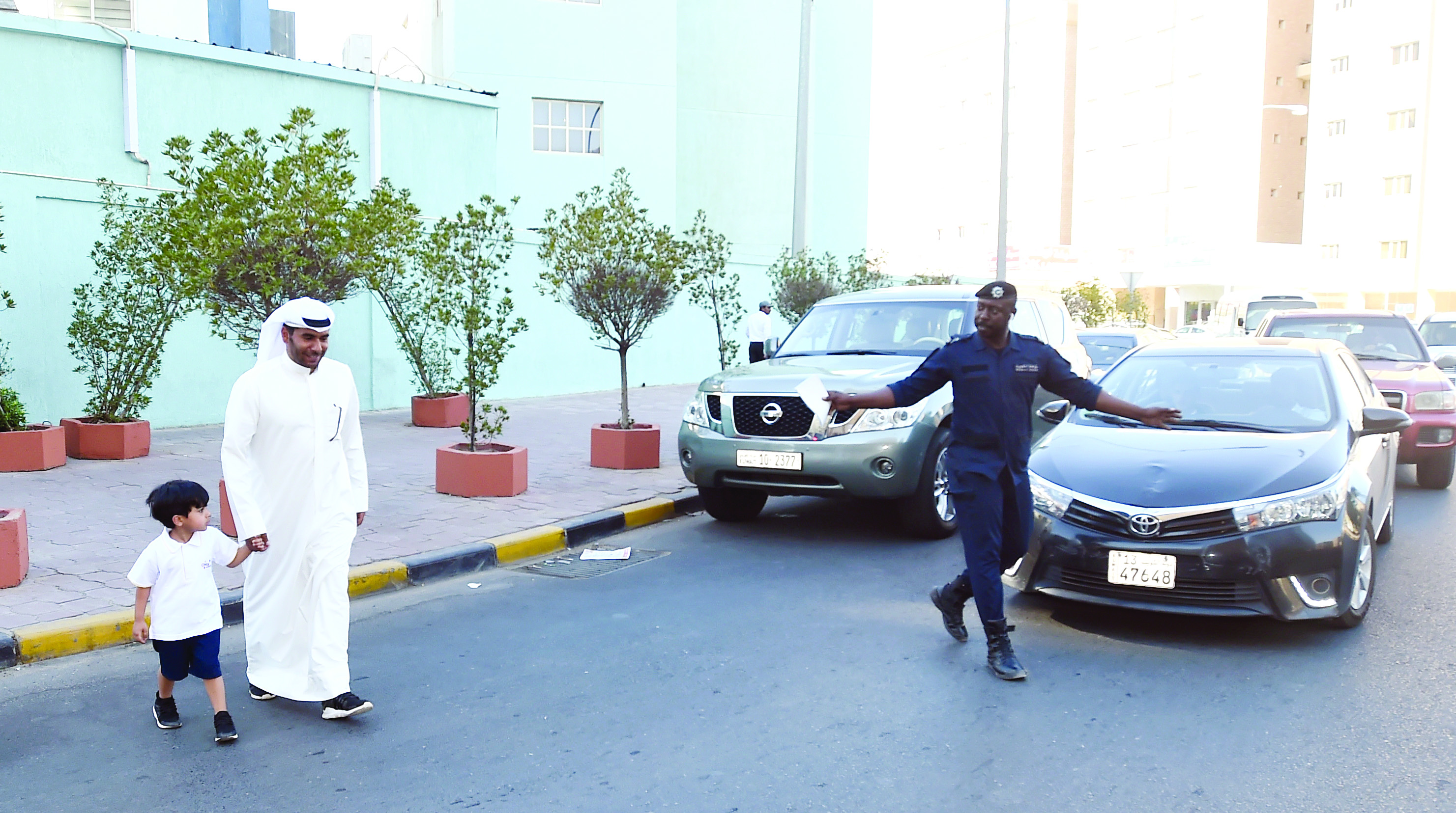 شرطي يوقف المرور لعبور ولي أمر وطفله                                                	              (تصوير نايف العقلة)