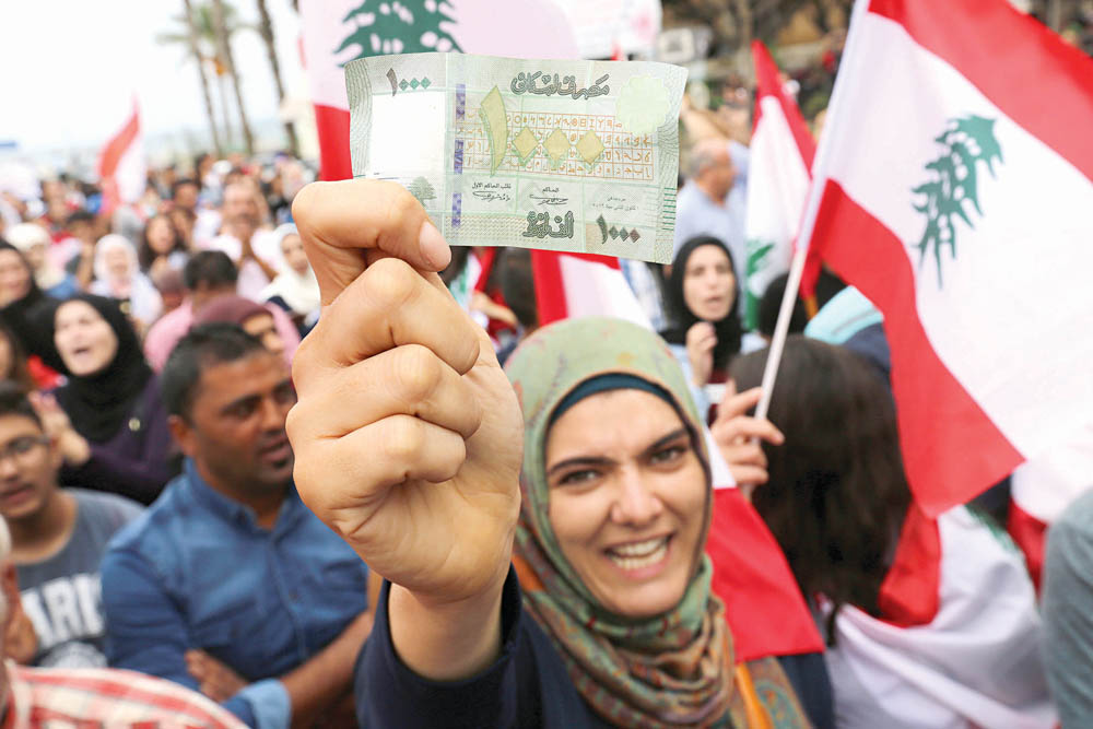 متظاهرة لبنانية تحمل ألف ليرة خلال الاحتجاجات في صور أمس	 (رويترز)