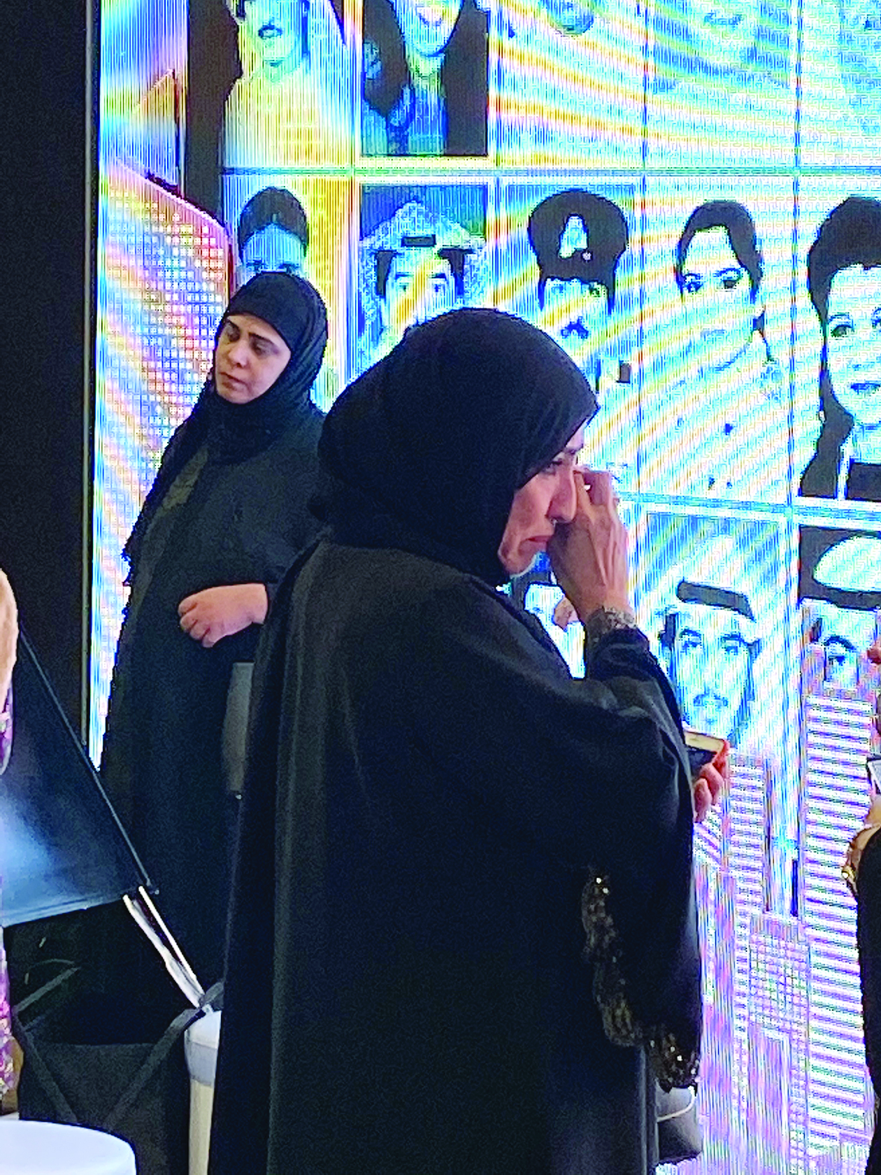 أم فيصل تبكي أمام صورة ولدها على الجدارية