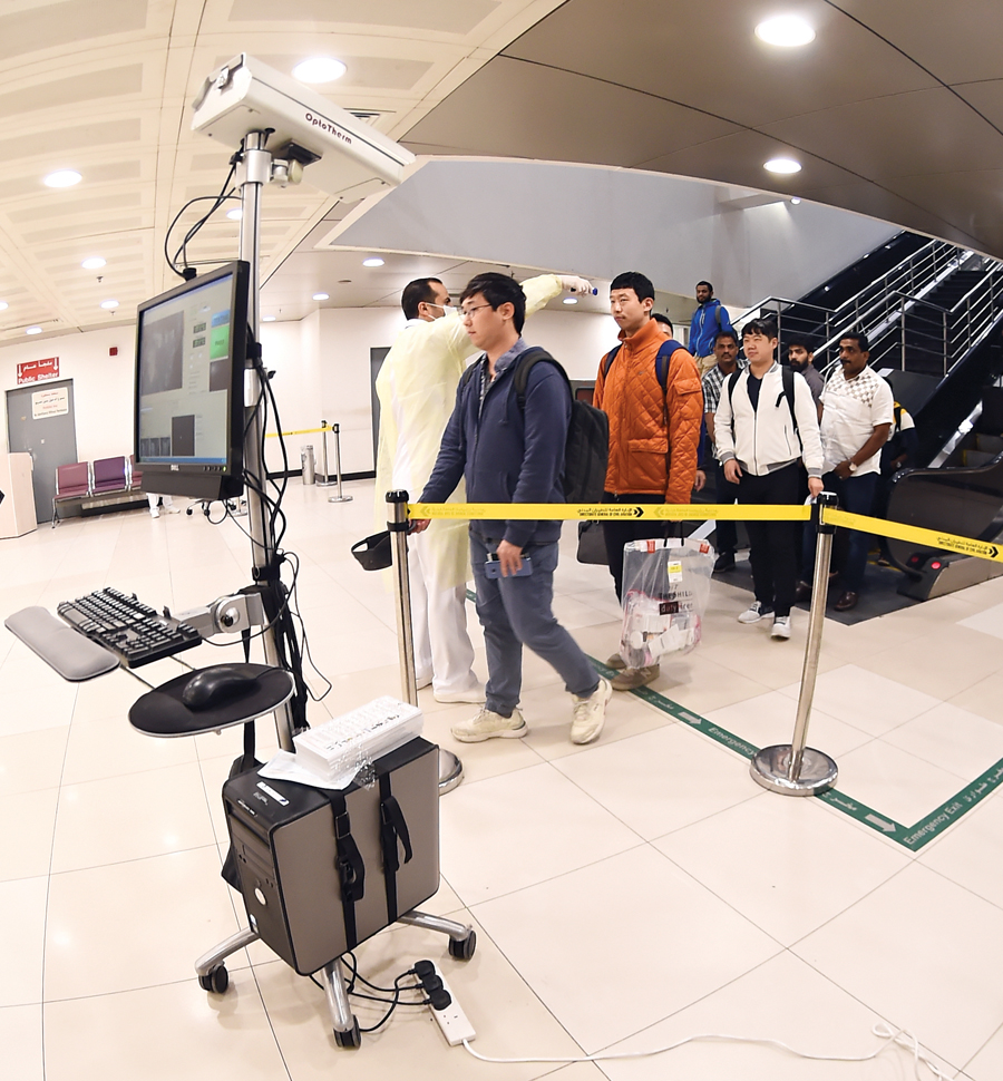 وصول آسيويين إلى صالة القادمين وأمامهم الكاميرا الحرارية	 (تصوير أسعد عبدالله)