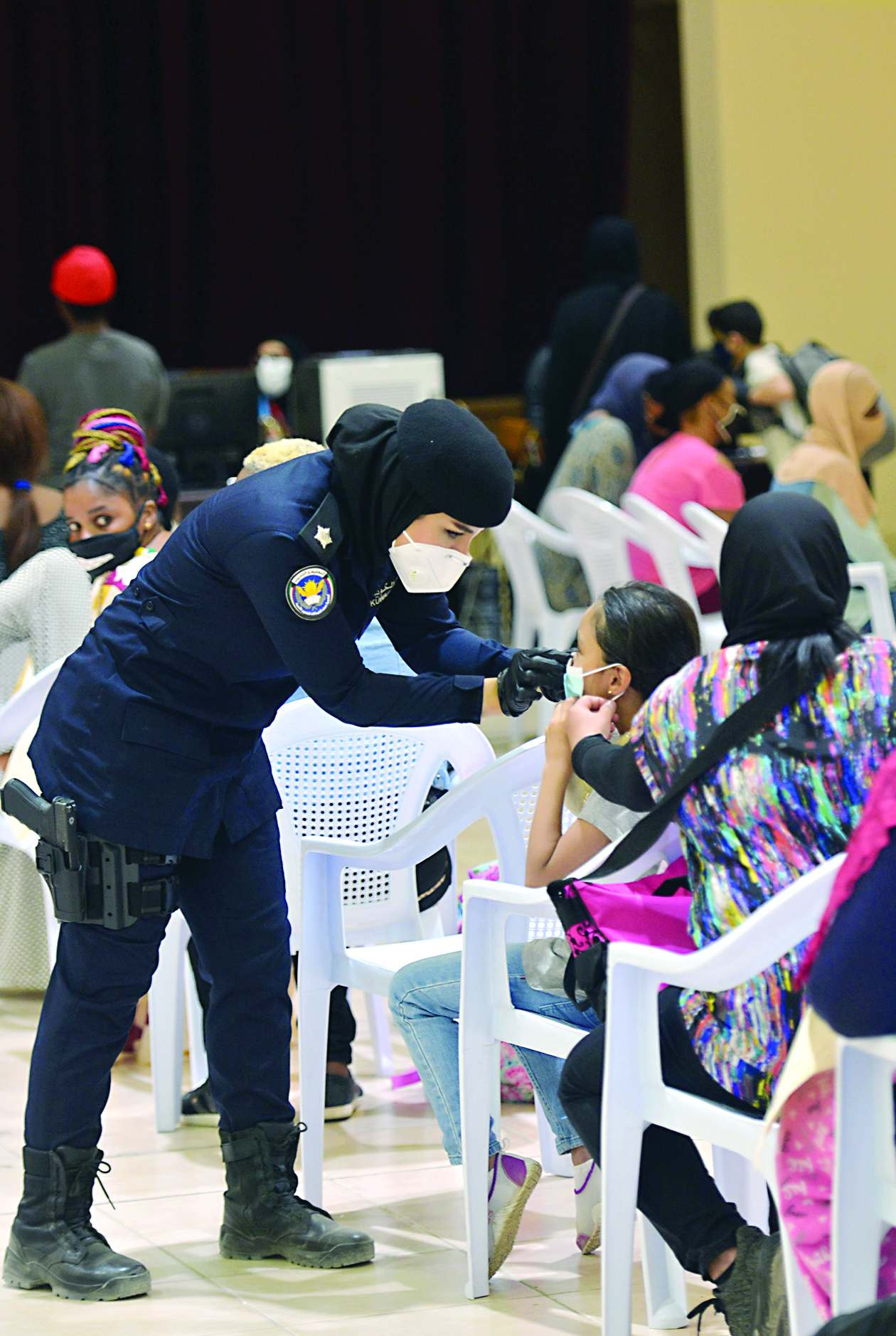 ضابطة تعدل الكمامة لطفلة حضرت مع والدتها