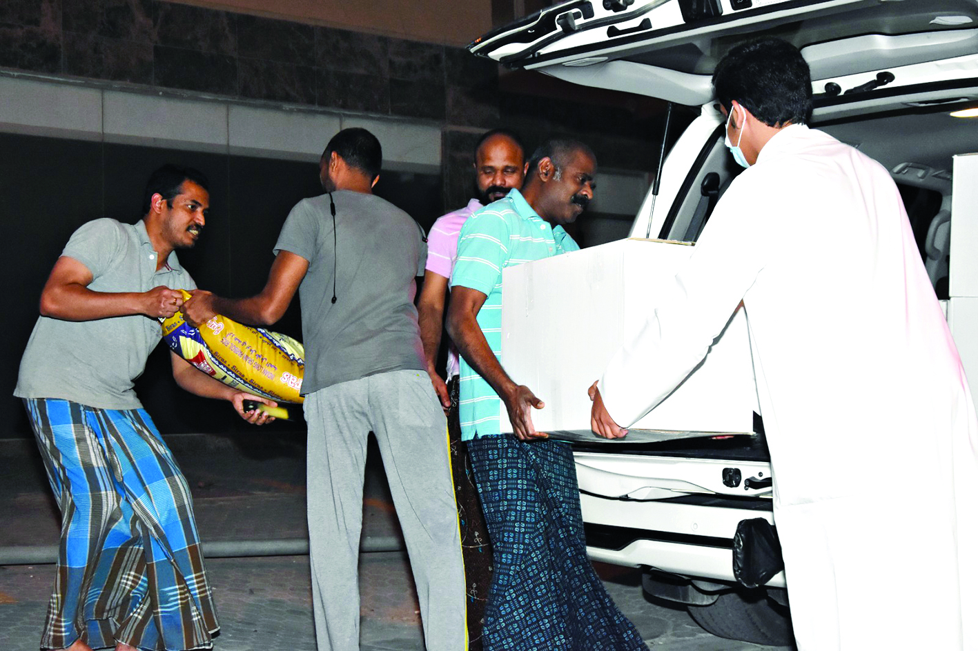 أحد المتطوعين لدى تسليمه السلال لبعض العمال المتضررين