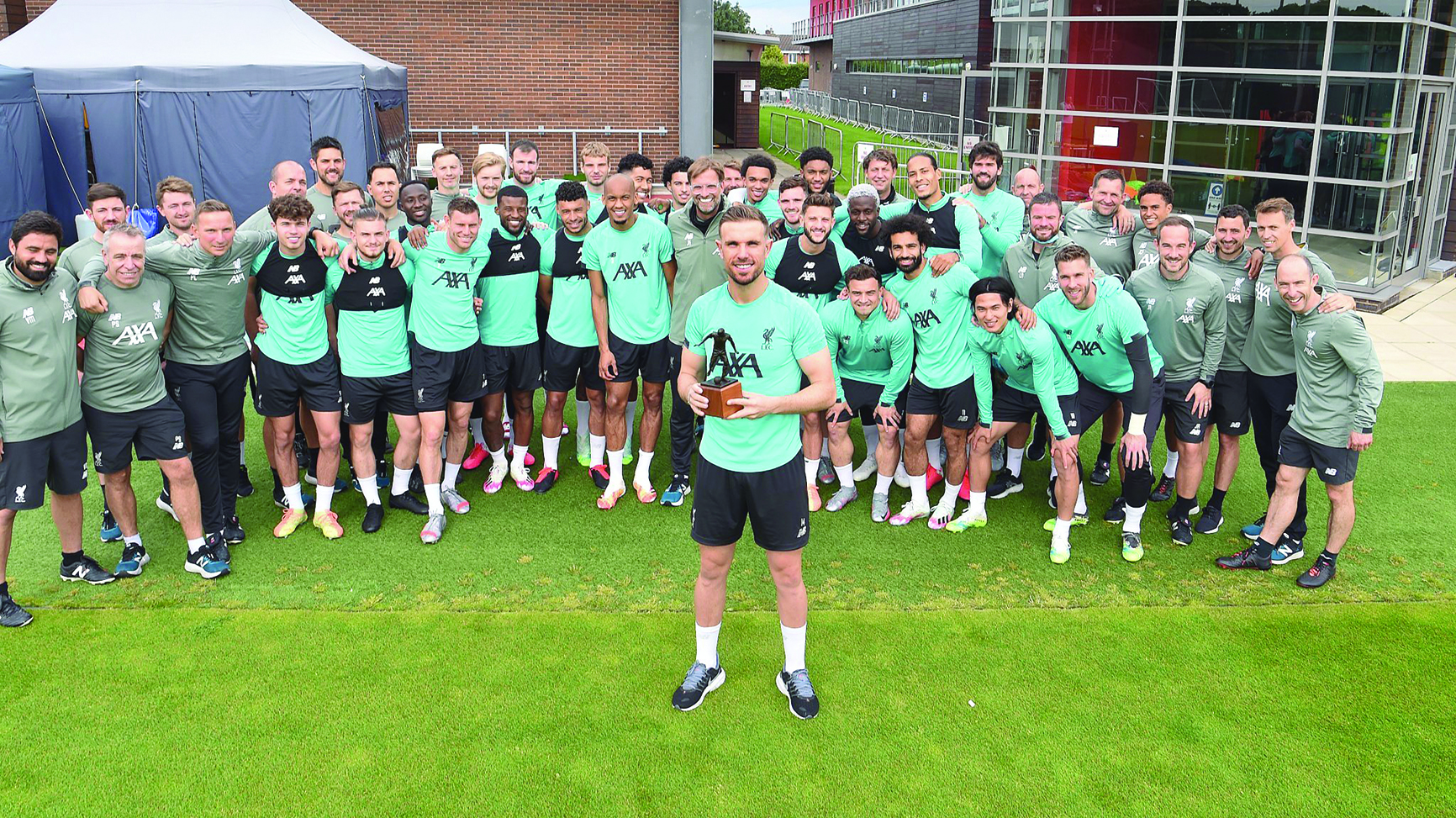 جوردان هندرسون حاملاً جائزة أفضل لاعب أمام زملائه وأفراد الجهاز الفني لليفربول 