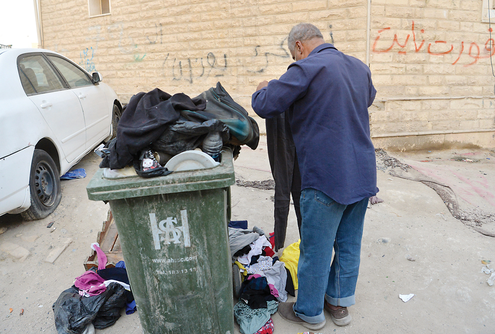رجل يبحث عن ملابس في حاوية القمامة 