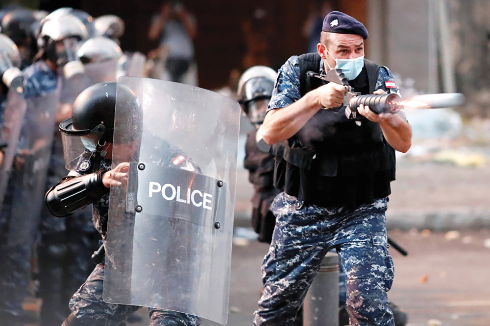 عنصر أمن لبناني يطلق قنبلة مسيلة للدموع في اتجاه المتظاهرين في وسط بيروت أمس	 (رويترز)