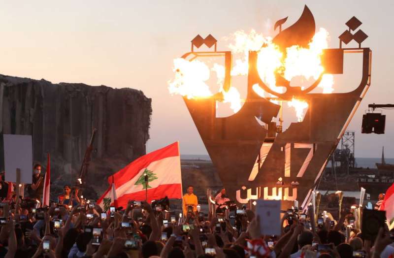 متظاهرون يلتقطون صوراً لمنحوتة "ثورة" بالقرب من مرفأ بيروت أمس (رويترز)