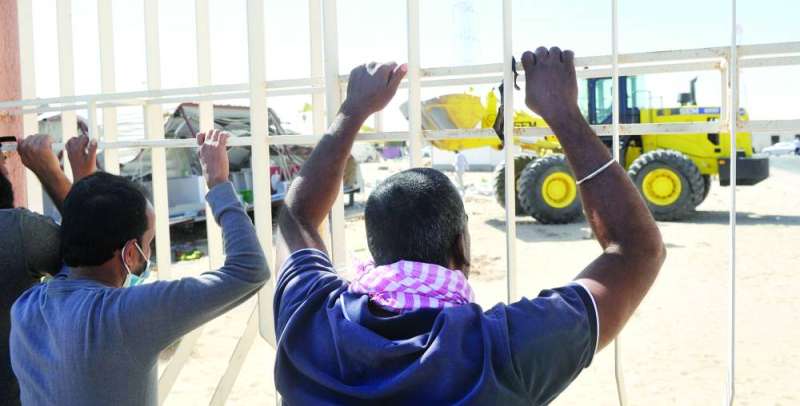 عمالة وافدة تنظر حملة إزالة التعديات من خلف أسوار المدينة العمالية 		  (تصوير سعود سالم)