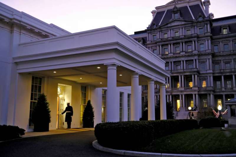 صورة لأحد جنود مشاة البحرية وهو يفتح باب الجناح الغربي في إشارة إلى أن الرئيس دونالد ترامب موجود في المكتب البيضاوي (رويترز)