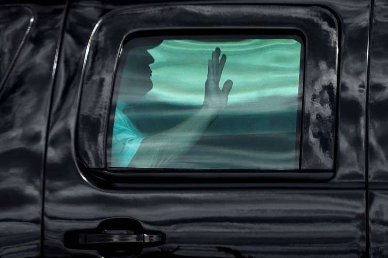 ترامب يلوّح من خلف زجاج سيارته المدرعة أثناء مغادرته ناديه للغولف في ويست بالم بيتش أول من أمس (رويترز)