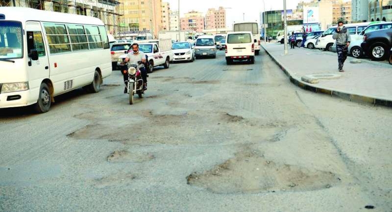 أحد الشوارع المتهالكة في خيطان... وفي الإطار حماد يعاين حفرة وسط الطريق	(تصوير نايف العقلة)