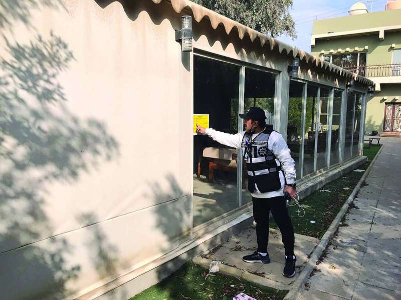 أحد أفراد الضبطية يضع ملصق انذار على خيمة مخالفة