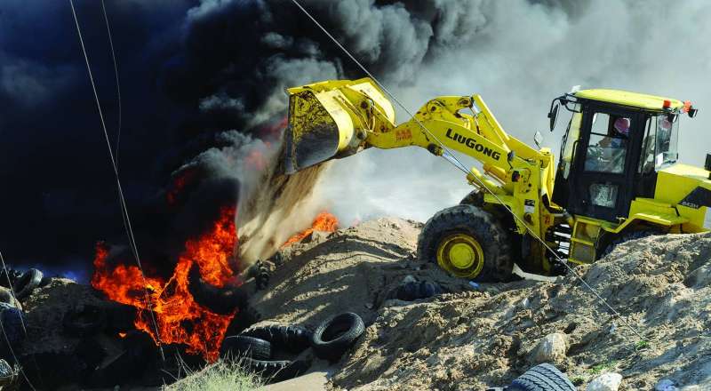 جهود كبيرة لفرق الإطفاء خلال إخماد الحريق في موقع إطارات إرحية أمس 		 (تصوير سعود سالم)