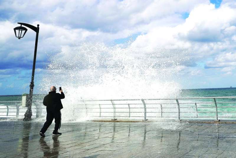 رجل يلتقط صورة لأمواج عالية على شاطئ البحر المهجور في بيروت في يوم عاصف (ا ف ب)