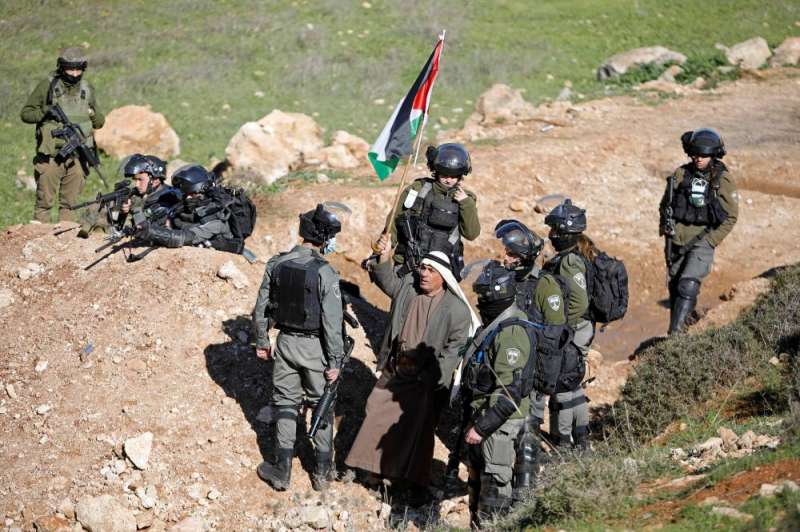 قوة إسرائيلية تحاصر متظاهراً يحمل العلم الفلسطيني في بيت دجن بالضفة الغربية (رويترز)