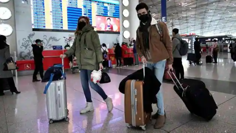 مسافرون يرتدون كمامات في مطار بكين الدولي