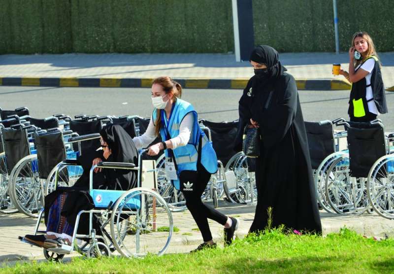 متطوعة تدفع الكرسي المتحرك لإحدى السيدات