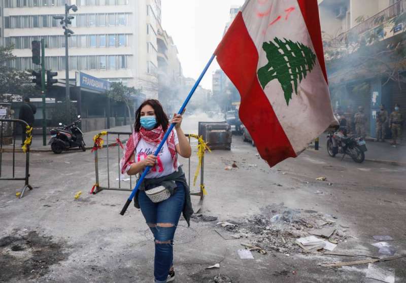 متظاهرة ترفع العلم اللبناني خلال احتجاجات في وسط بيروت (رويترز)