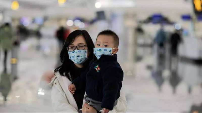 أم وطفلها يرتديان كمامات في مطار بكين