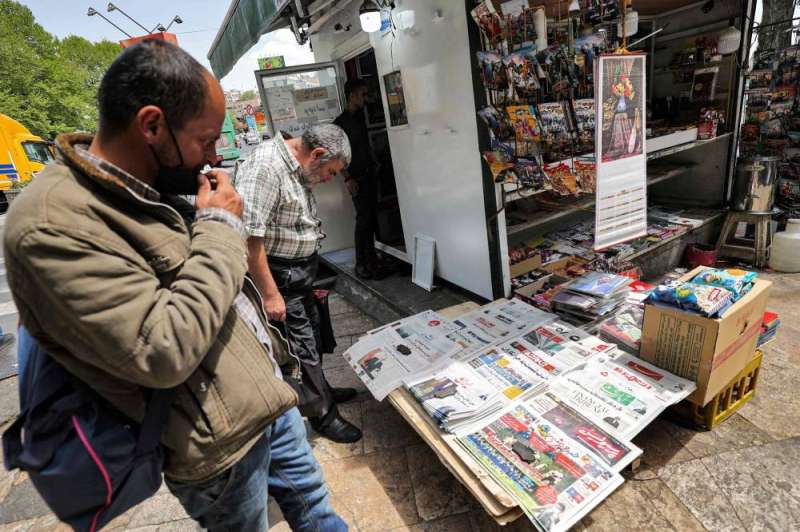 إيرانيان يطالعان أغلفة الصحف المحلية من أمام أحد الأكشاك في طهران 	 (أ ف ب)