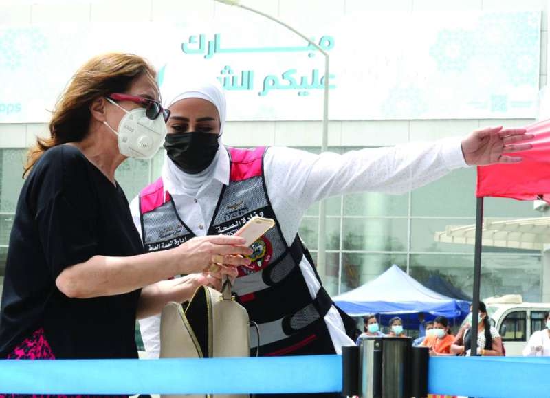 إحدى كوادر الصحة العامة ترشد سيدة إلى مكان التطعيم في مركز أرض المعارض (تصوير أسعد عبدالله)