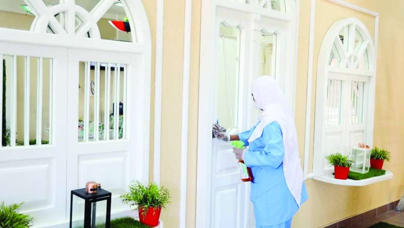 عاملة تنظف وتعقم الأبواب والنوافذ