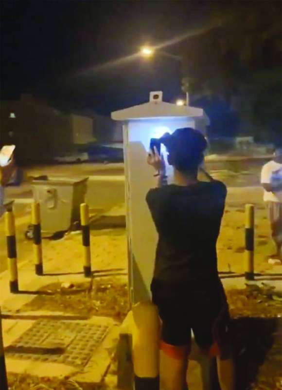 أحد العابثين يوجه ضوء الهاتف على صندوق الخلايا الذكية