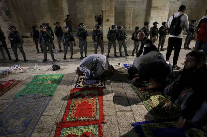 فلسطينيون يؤدون الصلاة بينما تتجمع الشرطة الإسرائيلية خلال المواجهات في المجمع الذي يضم المسجد الأقصى ليل الجمعة - السبت (رويترز)
