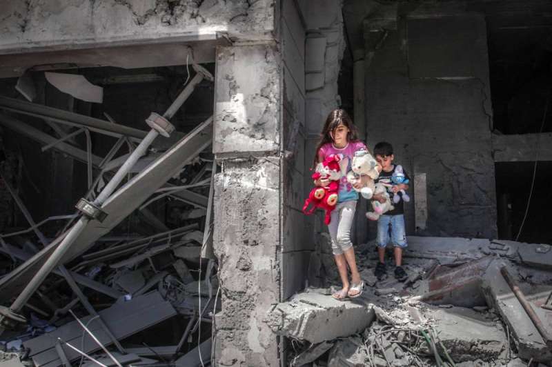 طفلان فلسطينيان «يُنقذان» العابهما في برج الجوهرة السكني في غزة (أ ف ب)