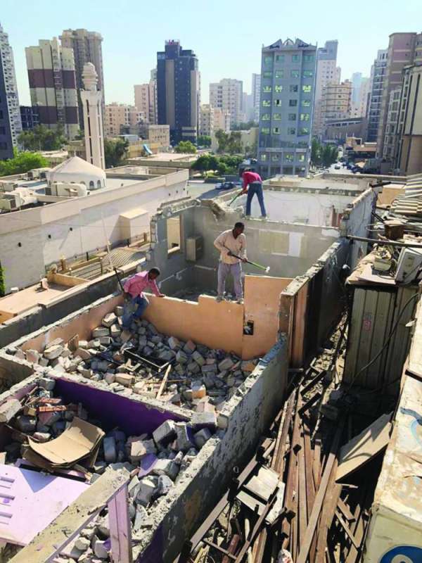 عمال يقومون بإزالة مخالفات عقار في العاصمة