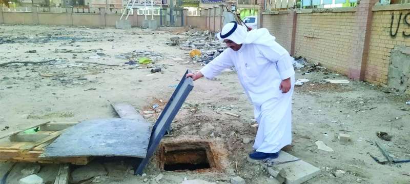 الزميل عزيز أحمد يعاين منهول المدرسة المهجورة في خيطان ( تصوير أسعد عبدالله)