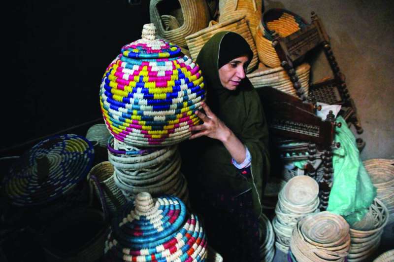 امرأة تحمل قفصاً مصنوعاً من سعف النخيل في منزلها بقرية بالفيوم