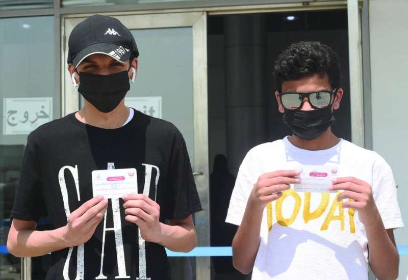 فتيان يعرضان بطاقتي تطعيمهما
