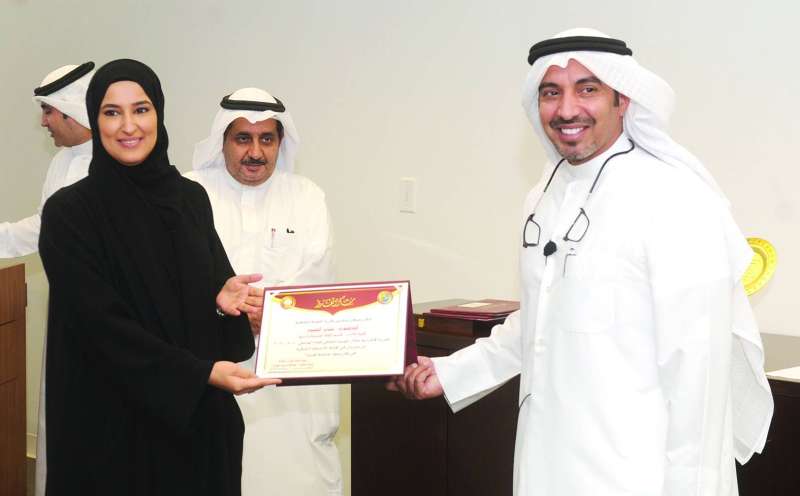 الهاجري مكرماً منسقة قسم اللغة العربية بالكلية 	(تصوير سعود سالم)
