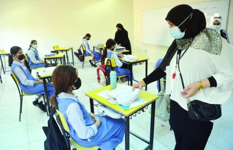 معلمة في مدرسة متوسطة توزع كتباً على الطلبات