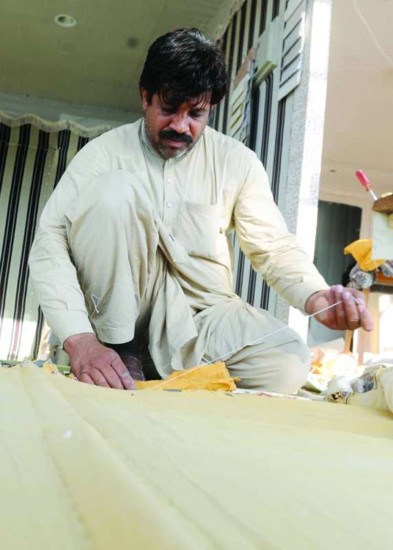 عامل يقوم بخياطة خيمة جديدة
