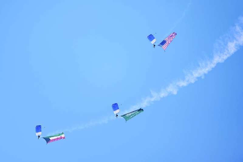 مظليون يحملون أعلام الدول المشاركة في التمرين
