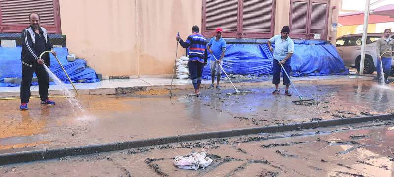 تنظيف أحد المواقع من الطين الذي حملته مياه الأمطار في العقيلة 	(تصوير أسعد عبدالله)
