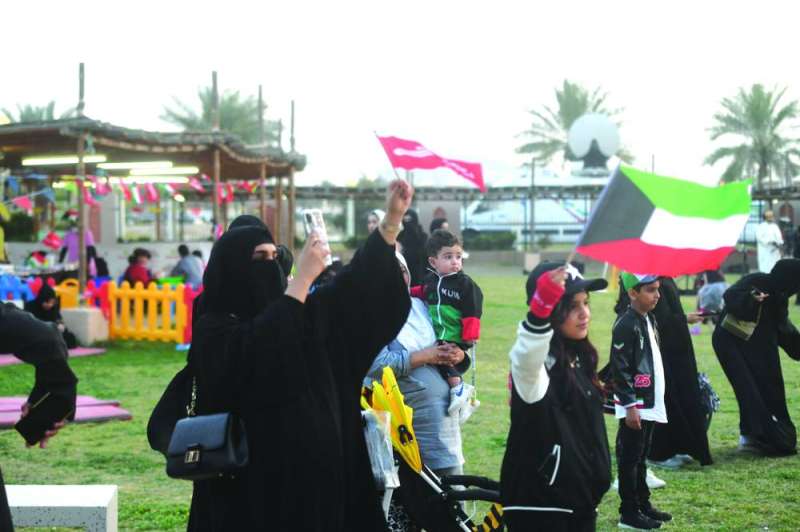 نساء وأطفال يرفعون أعلام الكويت
