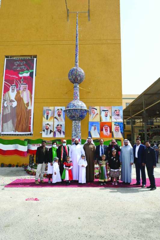 إبراهيم متوسطاً مسؤولي المدرسة أمام مجسم أحد أبراج الكويت