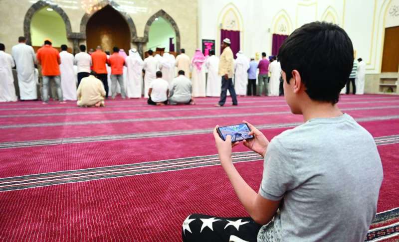 
فتى يلعب بهاتف في أحد المساجد فيما المصلون يؤدون التراويح 	(تصوير نايف العقلة)
