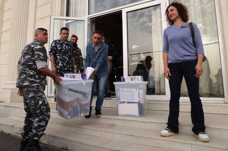 عناصر أمنية تنقل مع المدنيين صناديق الاقتراع وسط بيروت (أ ف ب)
