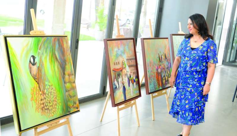 سلوى القائد تقف أمام لوحاتها