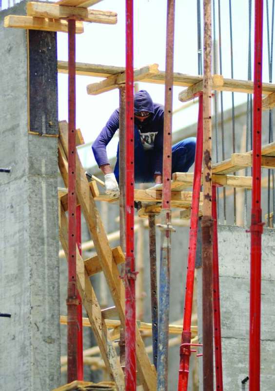 
عامل بين أعمدة الحديد والخشب تحت الشمس
