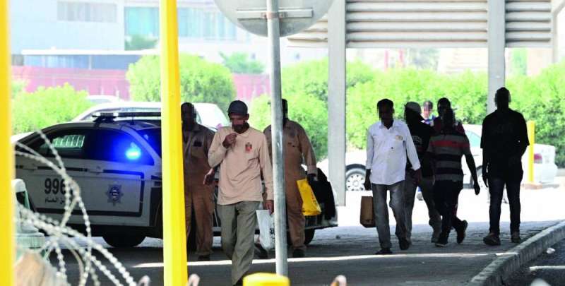 عمال يمرون من أمام سيارة شرطة في المنطقة
