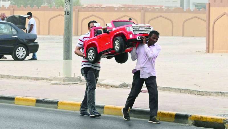 عاملان يحملان سيارة لعبة لتوصيلها لأحد الزبائن
